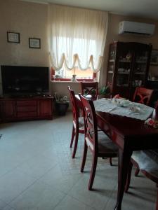 una sala da pranzo con tavolo, sedie e TV di La Quercia a Cosenza