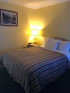 a hotel room with a large bed with a lamp at Sunset Motel in Athens