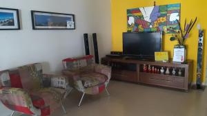 uma sala de estar com 2 cadeiras e uma televisão de ecrã plano em Piratas do Sol Hostel no Recife