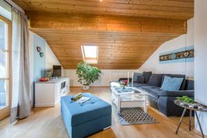 a living room with a blue couch and a wooden ceiling at Hochgallinger Hof in Siegsdorf