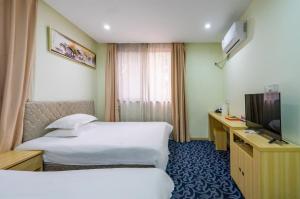 Cette chambre comprend deux lits et une télévision. dans l'établissement Hangzhou Memory Travel International Hotel-Edge Westlake, à Hangzhou