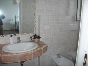 a bathroom with a sink and a mirror and a toilet at Baia Scirocco Bed and Breakfast in Peschici