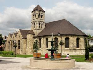 a church with a fountain in front of a building at Maison proche de Paris 15 minutes in Deuil-la-Barre