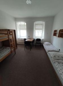 a room with two bunk beds and a table and chairs at Hostel Kašperské Hory in Kašperské Hory +59 photos