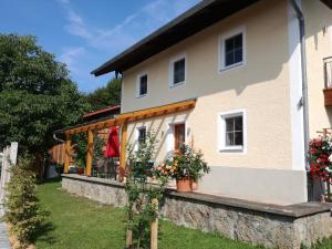 a house with a porch and flowers in the yard at Landhof Ella - Ferienhaus vor den Toren Salzburgs in Petting