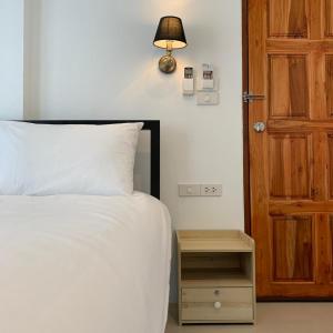1 dormitorio con cama blanca y puerta de madera en Chaweng best hotel and hostel samui, en Chaweng
