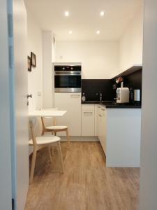 a kitchen with white cabinets and a table and chairs at Apartment Jakimovski in Wuppertal
