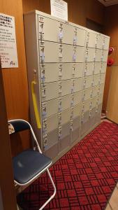 a wall of lockers with a chair in a room at Ave Tennoji Hotel in Osaka