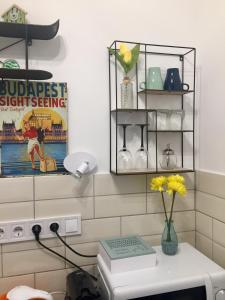 un baño con un cartel en la pared y un jarrón con flores amarillas en Buda Boutique Apartment en Budapest