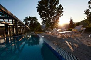 - une piscine avec des chaises et un coucher de soleil dans l'établissement Rikli Balance Hotel – Sava Hotels & Resorts, à Bled