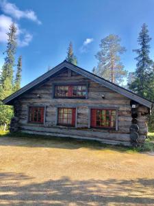 Cabaña de madera con ventanas rojas en un bosque en Villa Karhuntähti, en Luosto