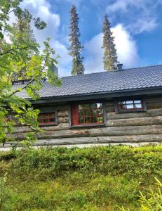 uma cabana de madeira com janelas vermelhas e um telhado em Villa Karhuntähti em Luosto