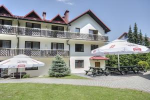 two umbrellas and benches in front of a building at Pensjonat BELVEDERE in Szczyrk