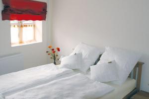 Cama blanca con almohadas blancas y ventana en Gästehaus Oh-La-La en Wilster