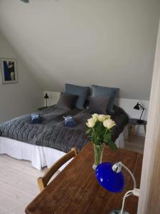 Un dormitorio con una cama y una mesa con flores. en Hvirrekærgaard, midt i naturen. en Hirtshals