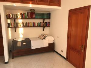 a small bedroom with a bed and shelves with books at Casa Memo in Vernazza