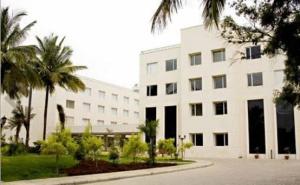 a large white building with palm trees in front of it at Evoma in Bangalore
