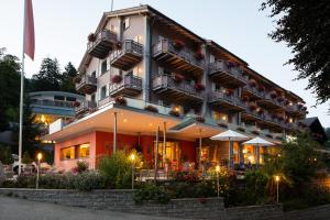 un edificio de hotel con flores y plantas delante de él en Parkhotel Schoenegg, en Grindelwald