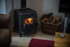 einen Herd im Wohnzimmer mit einem Korb in der Unterkunft Bayview Farm Holiday Cottages in Bushmills