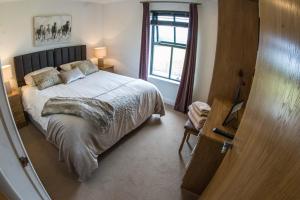 Un dormitorio con una cama grande y una ventana en Bayview Farm Holiday Cottages, en Bushmills