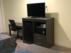 a tv on a stand with a desk and a chair at Gila Bend Lodge in Gila Bend