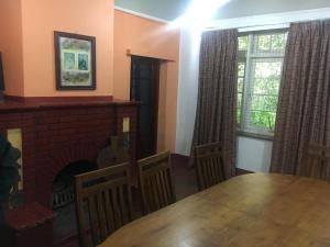 uma sala de jantar com uma mesa e uma lareira em Devon Fall Cottage em Dimbula