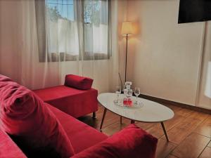 ein Wohnzimmer mit einem roten Sofa und einem Tisch in der Unterkunft The Little Gem Under The Rocks in Kastraki
