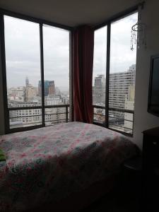 ein Schlafzimmer mit einem Bett und einem großen Fenster in der Unterkunft UNA HABITACIÓN PRIVADA con BAÑO PRIVADO en CENTRO HISTÓRICO in Santiago