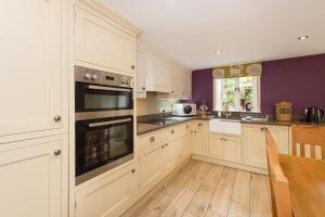 a kitchen with white cabinets and a purple wall at Drake Cottage in Whitby +32 photos