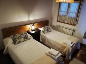 a bedroom with two beds and a lamp and a window at LA ALDEA in Llanes