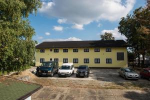 een geel gebouw met auto's ervoor geparkeerd bij Hostel M in Maribor