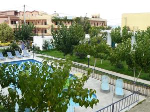 vistas a una piscina con sillas azules y árboles en Leonidas Studios & Apartments en Georgioupolis