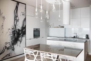 a white kitchen with a dining table and chairs at Vantage Point Apartament Sky Tower in Wrocław