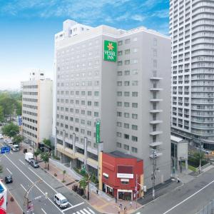 a large white building with a green sign on it at Vessel Inn Sapporo Nakajimakoen in Sapporo