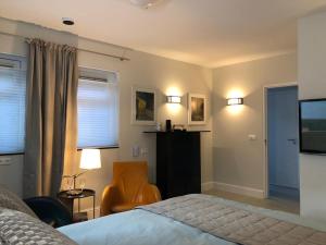a bedroom with a bed and a chair and a television at Modern Palace Emma Staete in Baarn