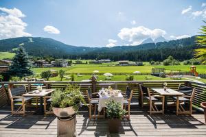 a patio with tables and chairs and a view of a field at Helmhotel in San Candido