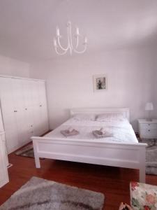 a white bed in a white bedroom with a chandelier at Studio apartment Zagorka Tkalčićeva street in Zagreb