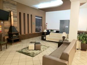 a lobby with a couch and a fireplace in a building at Presidente Hotel in Poços de Caldas