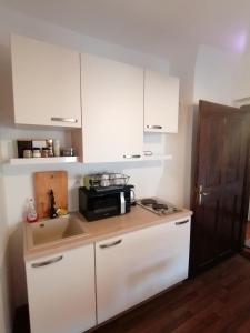 a kitchen with white cabinets and a sink and a microwave at Studio apartment Zagorka Tkalčićeva street in Zagreb