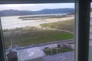 a view of a beach from a window at Apartamento Planeta 2º centro in O Porto de Espasante