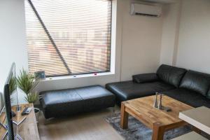 a living room with a black leather couch and a table at High End Apartments in Diamond Garden Building in Skopje