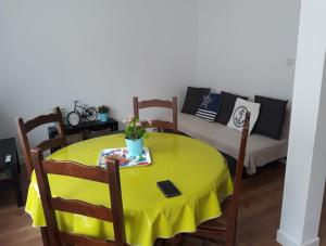uma mesa com uma toalha de mesa amarela e um sofá em Appartements Le Vivier 1er ou rez de chaussée em Boulogne-sur-Mer