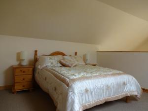 a bedroom with a bed and a wooden night stand at The Chalet at Corvally in Portrush