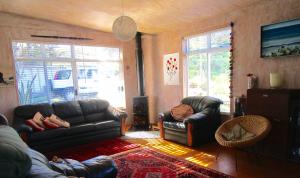 a living room with two couches and two windows at Mulberry Grove Retreat in Tryphena