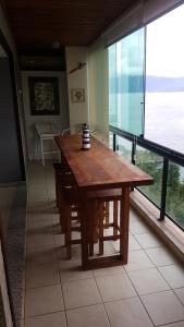 a wooden table in a room with large windows at Porto Real The View in Mangaratiba