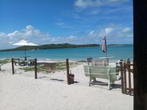 a beach with chairs and an umbrella and the ocean at Sítio Recanto Feliz - Pertinho da Igrejinha in Praia dos Carneiros