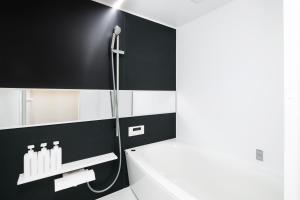 La salle de bains est pourvue de murs noirs et blancs et d'une douche. dans l'établissement SITSURAE OSAKA Shinsaibashi, à Osaka