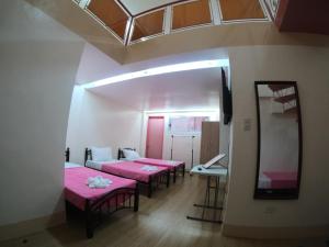 Havendwell Garden Resort في Bokbok: ثلاثة أسرة في غرفة ذات أغطية وردية