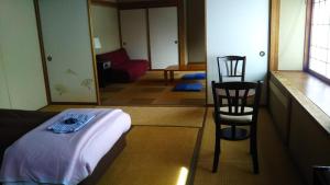 um quarto com uma cama e duas cadeiras em Sakka Sanso em Hakuba