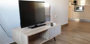 een flatscreen-tv op een houten standaard in een woonkamer bij Ria's Deluxe Apartments in Faliraki